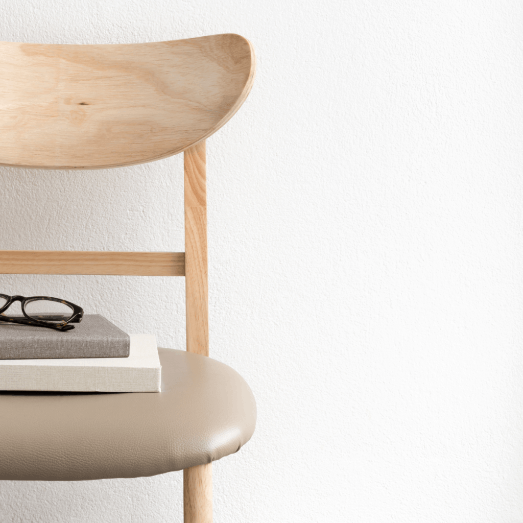 A chair with a book and glasses on it, crafted out of wood.