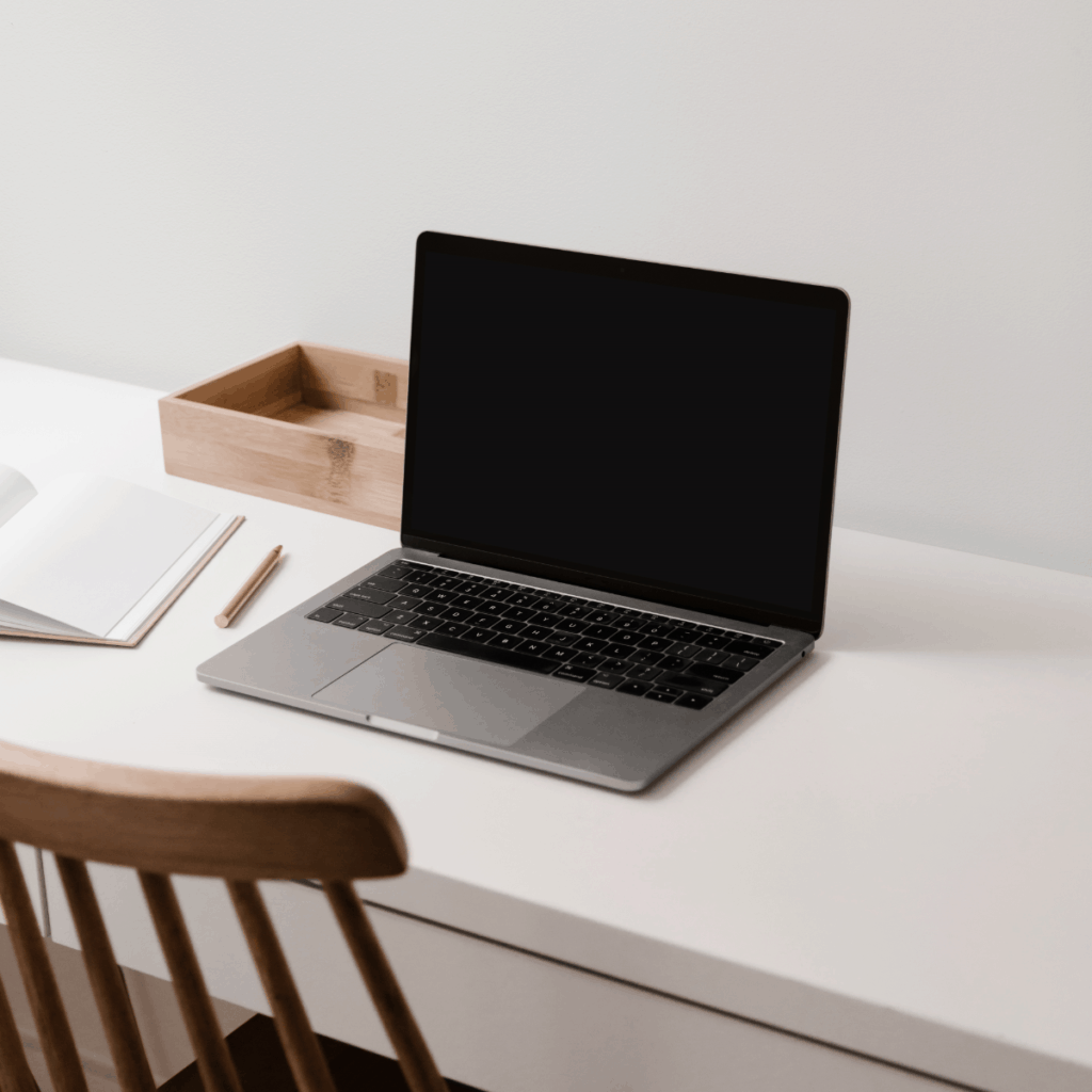 A white desk with a laptop and a notebook for a WordPress designer.