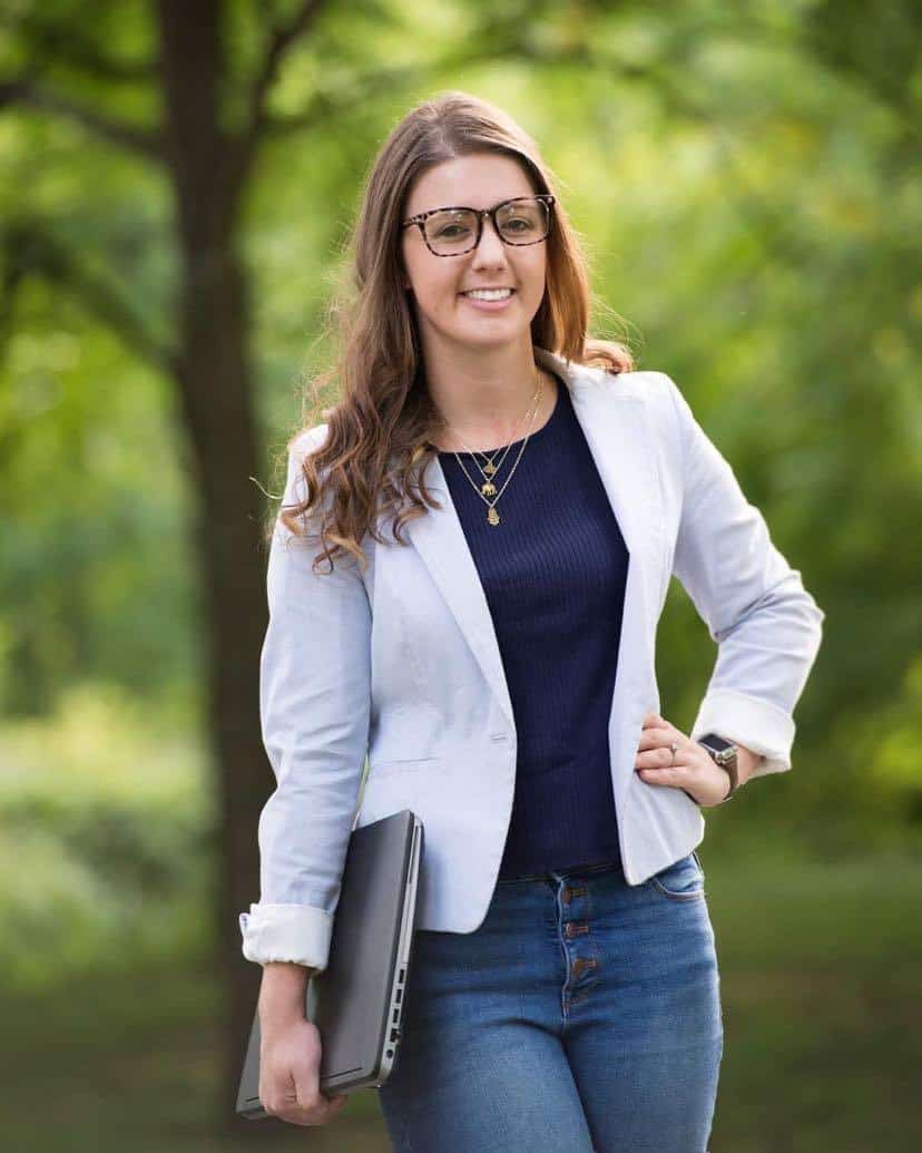 A young woman wearing glasses and a blazer, working as a WordPress designer.