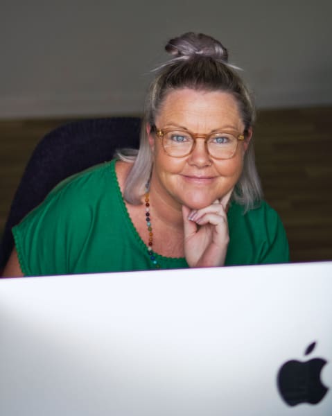A woman in glasses working as a WordPress designer.