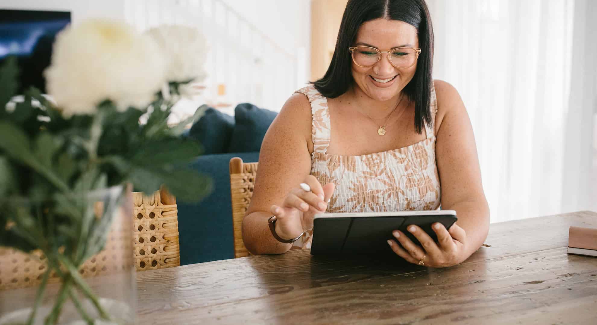 A woman at a table utilizing a tablet for WordPress development purposes.
