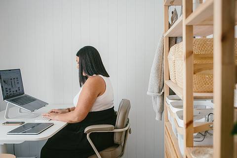 A WordPress developer woman sitting at a desk working on her laptop.