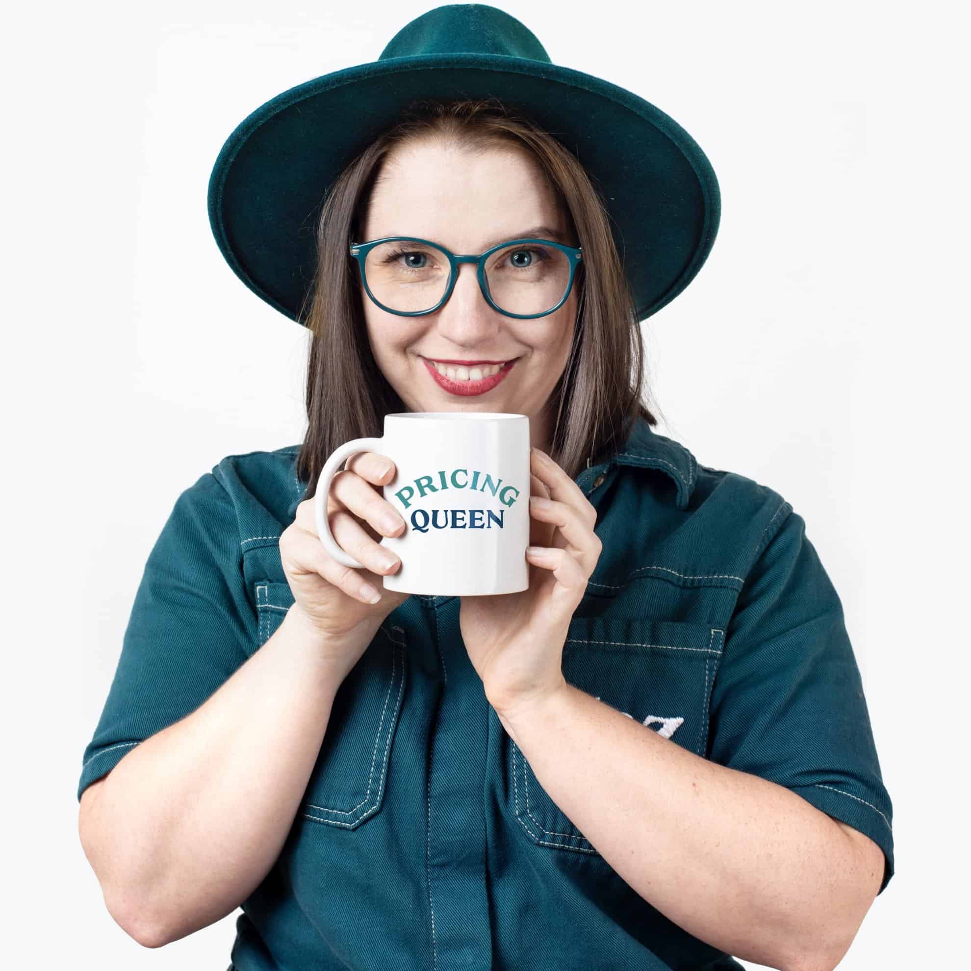 A woman wearing glasses and a hat holding a coffee mug.