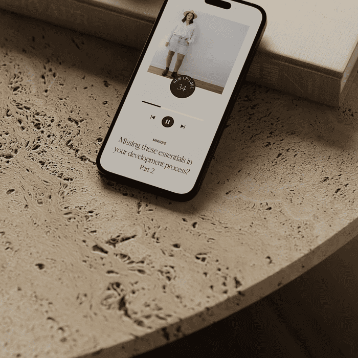 A phone is laying on a table next to a cup of coffee.